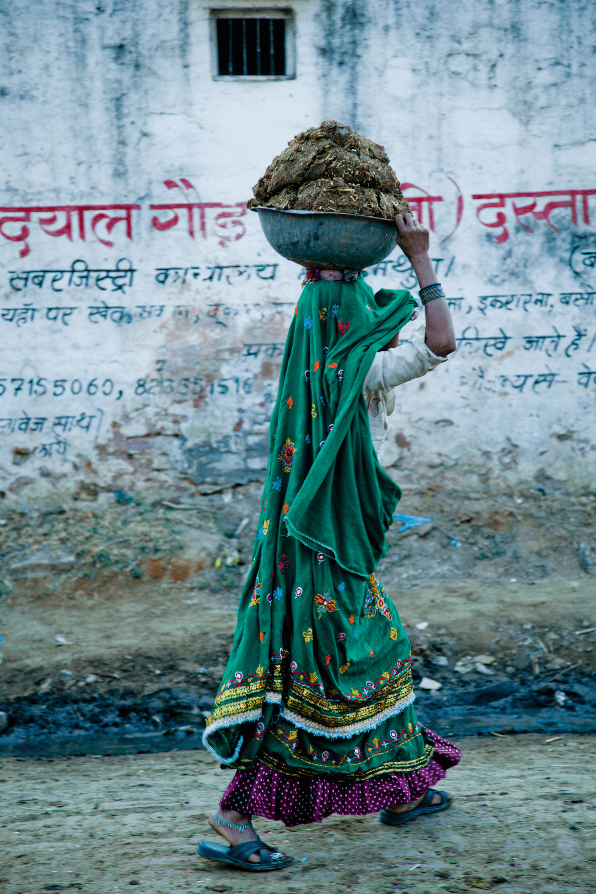 A woman carrying cow dung that she has collected for fuel #4/8